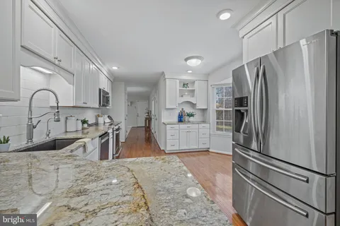 a kitchen with stainless steel appliances granite countertop a refrigerator sink and white cabinets
