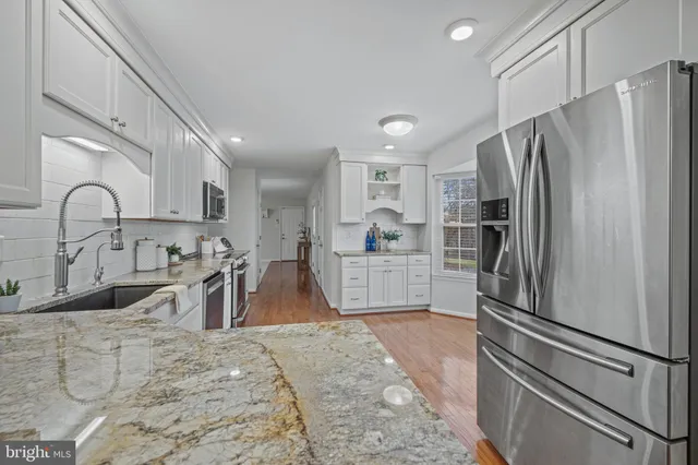 a kitchen with stainless steel appliances granite countertop a refrigerator sink and white cabinets