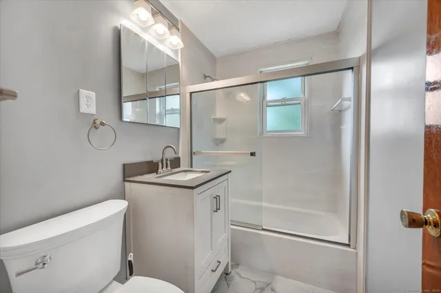 a bathroom with a granite countertop sink a toilet and a mirror