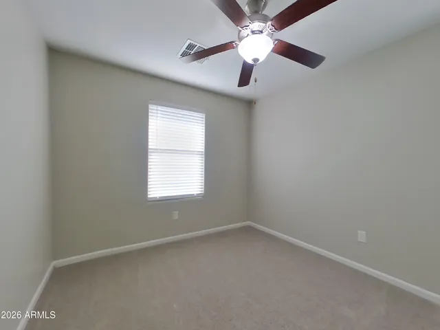 a view of an empty room and chandelier fan