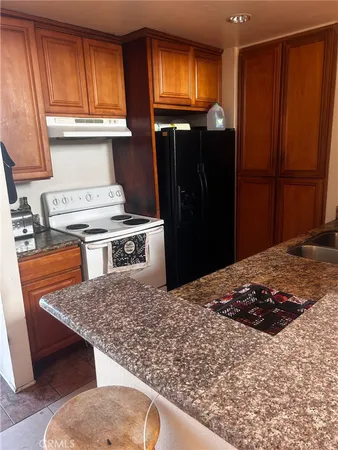 a kitchen with stainless steel appliances granite countertop a refrigerator a stove and a sink