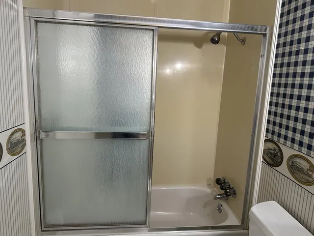 an empty room with chandelier fan and windows