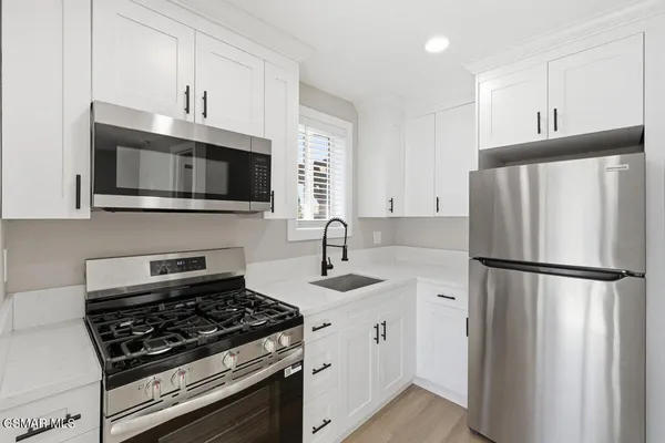 a kitchen with refrigerator a microwave a sink and cabinets
