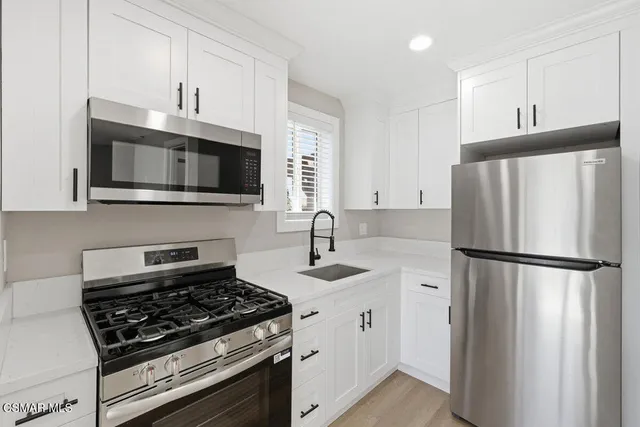 a kitchen with refrigerator a microwave a sink and cabinets