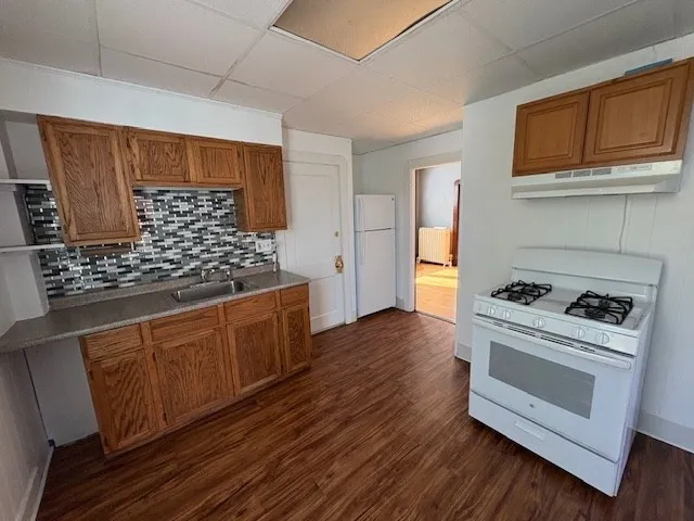 a kitchen with wooden floors and white appliances