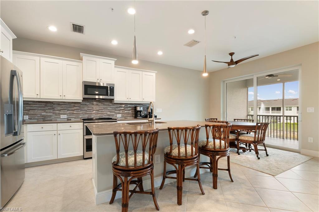 6954 Avalon Circle, Unit 706 Naples, FL 34112 - Photo 11 of 26 a kitchen with kitchen island granite countertop wooden cabinets and stainless steel appliances