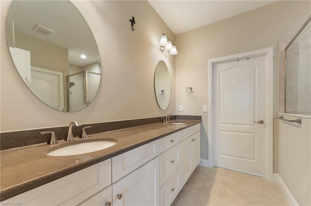 6954 Avalon Circle, Unit 706 Naples, FL 34112 - Photo 18 of 26 a bathroom with a granite countertop double vanity sink and a mirror