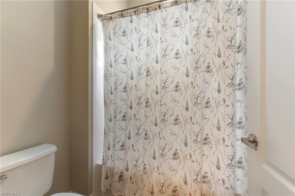 6954 Avalon Circle, Unit 706 Naples, FL 34112 - Photo 23 of 26 a bathroom with a toilet and a shower curtain