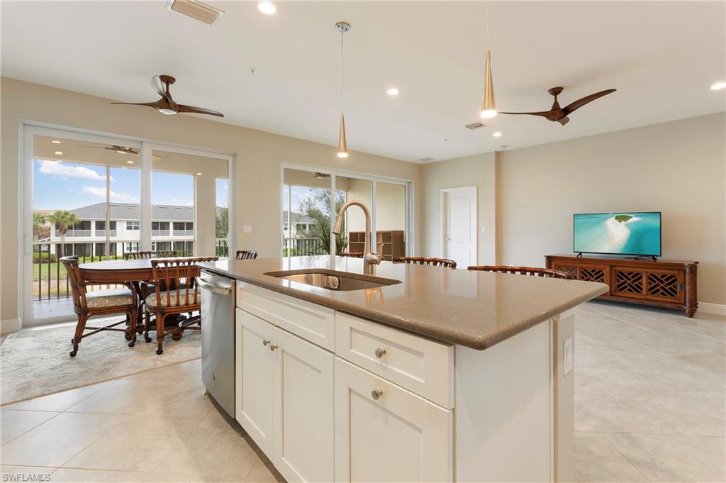 6954 Avalon Circle, Unit 706 Naples, FL 34112 - Photo 9 of 26 a kitchen with kitchen island a sink dining table and chairs