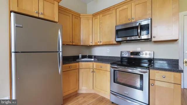 a kitchen with stainless steel appliances granite countertop white cabinets sink and a granite counter top