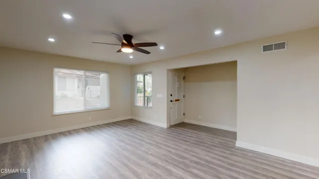 a view of an empty room with a window and wooden floor