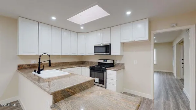 a kitchen with granite countertop a refrigerator cabinets and wooden floor