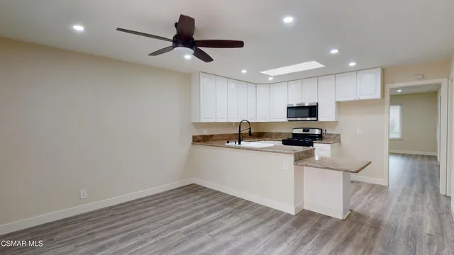 a kitchen with kitchen island granite countertop a sink cabinets and wooden floor