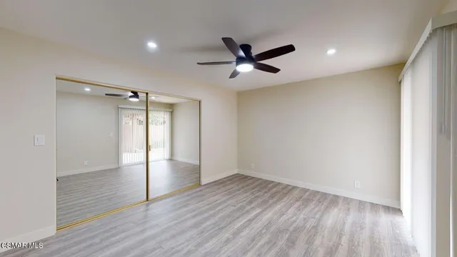 an empty room with wooden floor and a ceiling fan