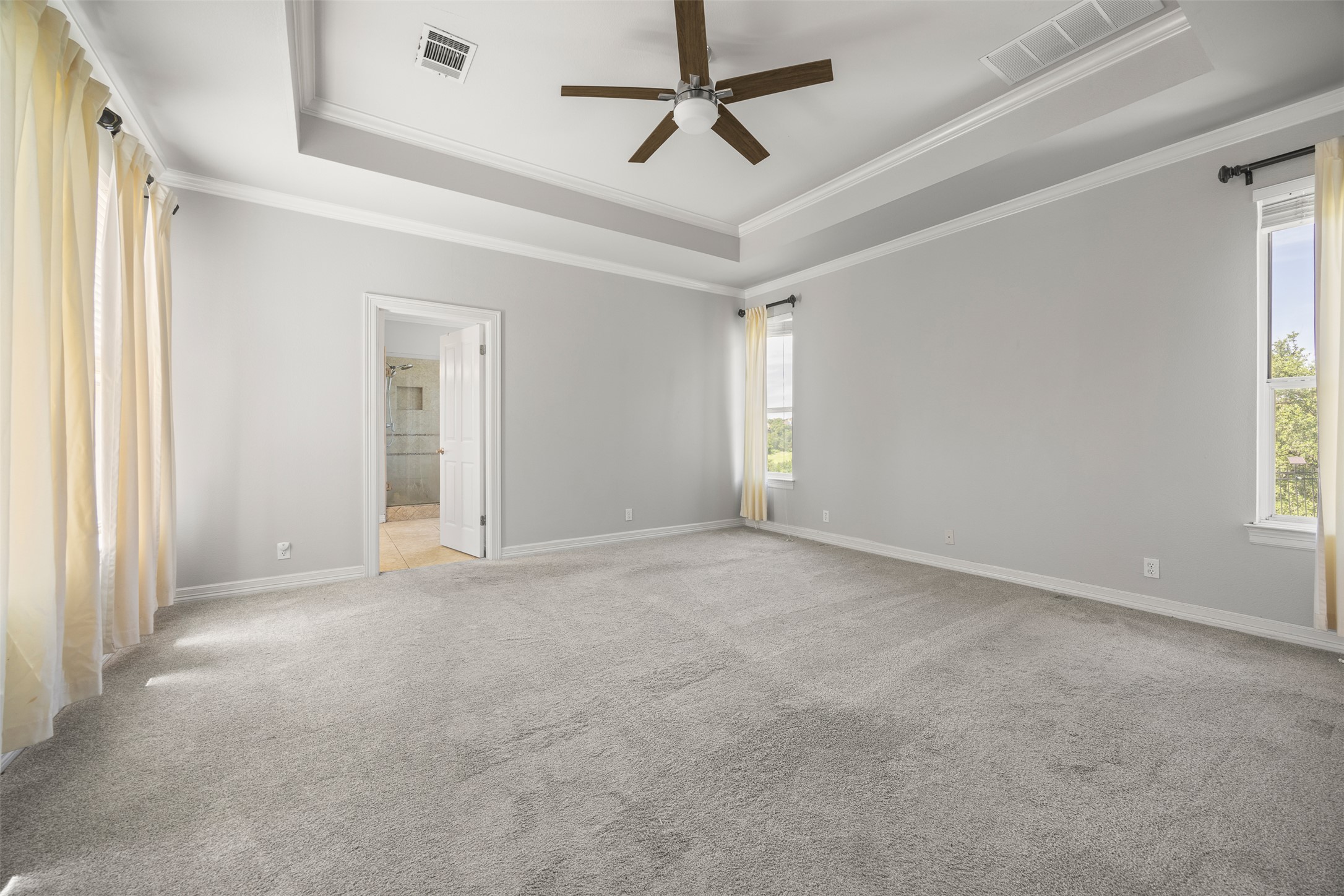9300 Simmons Road Austin, TX 78759 - Photo 7 of 17 An airy primary bedroom suite features a tray ceiling, recessed lighting, and soft carpeting throughout.