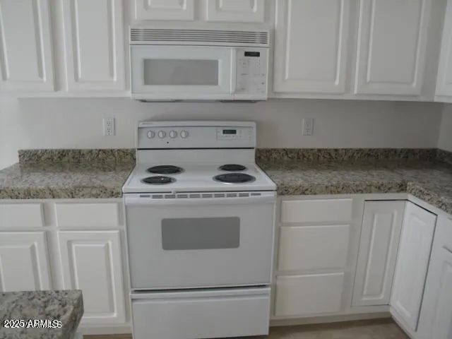 a kitchen with white cabinets and a refrigerator