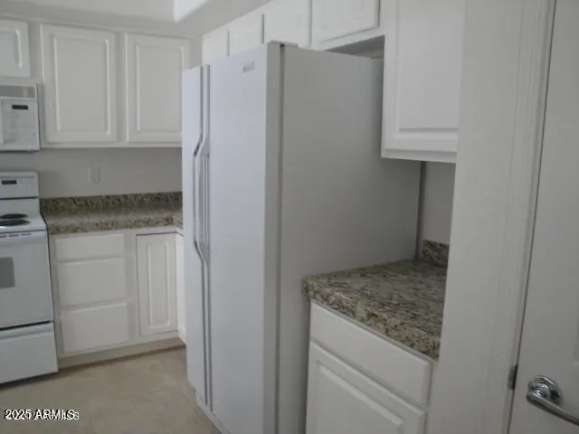 a kitchen with granite countertop white cabinets and a sink