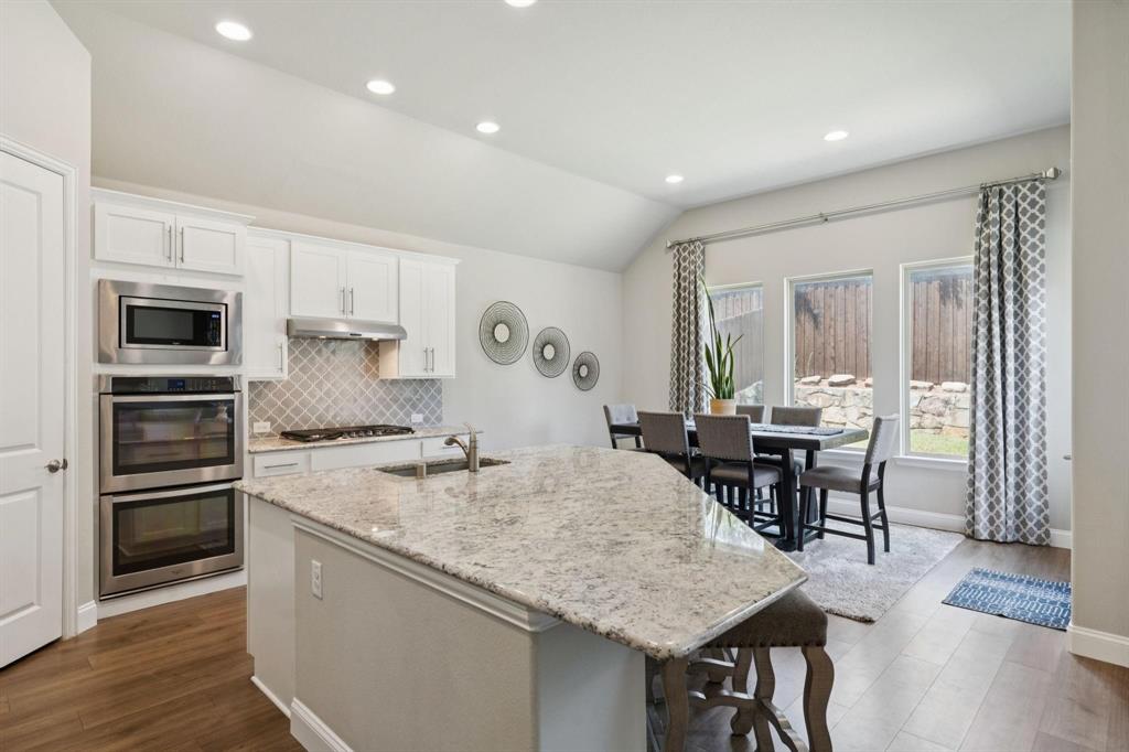2121 Demarsh Lane Corinth, TX 76210 - Photo 7 of 39 a kitchen with granite countertop a stove a sink a dining table and chairs