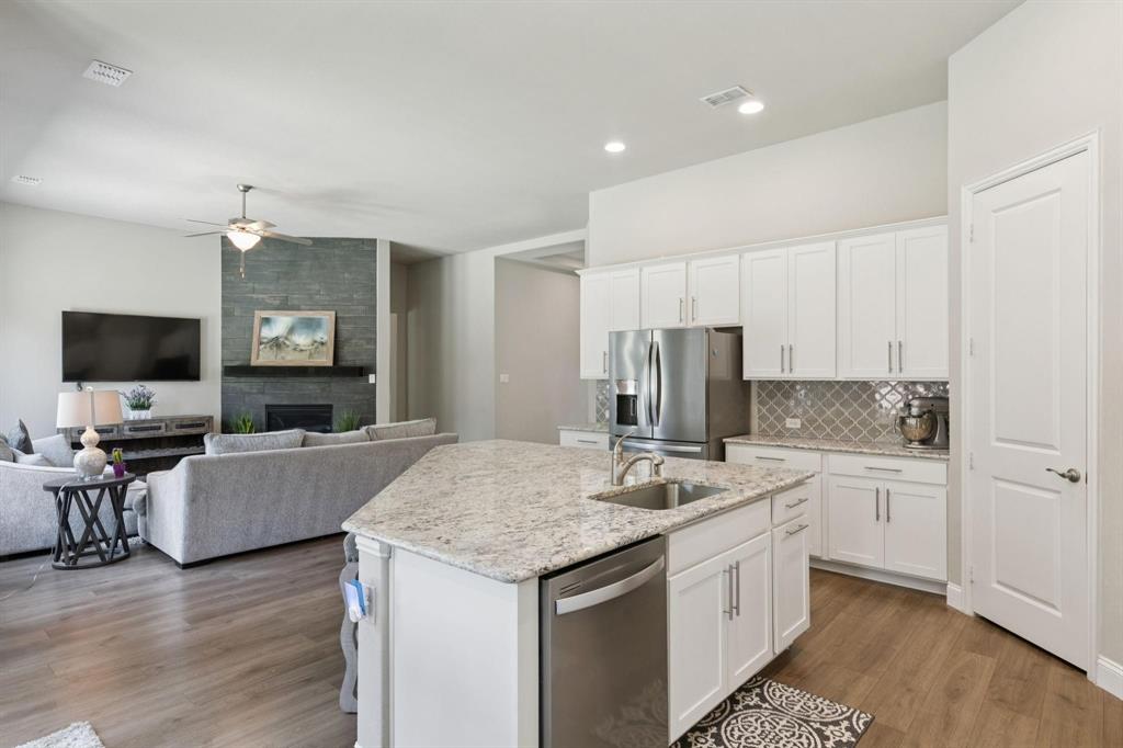 2121 Demarsh Lane Corinth, TX 76210 - Photo 8 of 39 a spacious kitchen with stainless steel appliances granite countertop a sink dishwasher a stove and a refrigerator with wooden floor