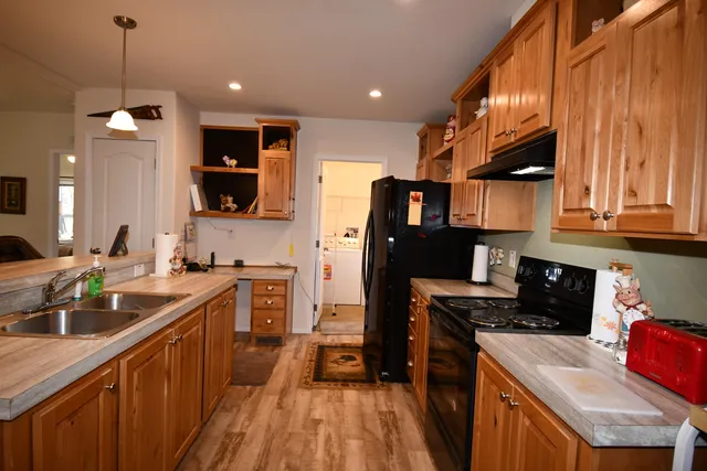 a kitchen with stainless steel appliances granite countertop wooden cabinets a sink dishwasher a stove and a refrigerator