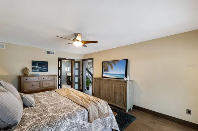 a bedroom with a large bed and a flat tv screen on dresser