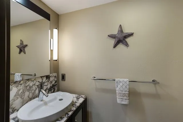 a bathroom with a granite countertop sink a toilet a mirror and shower