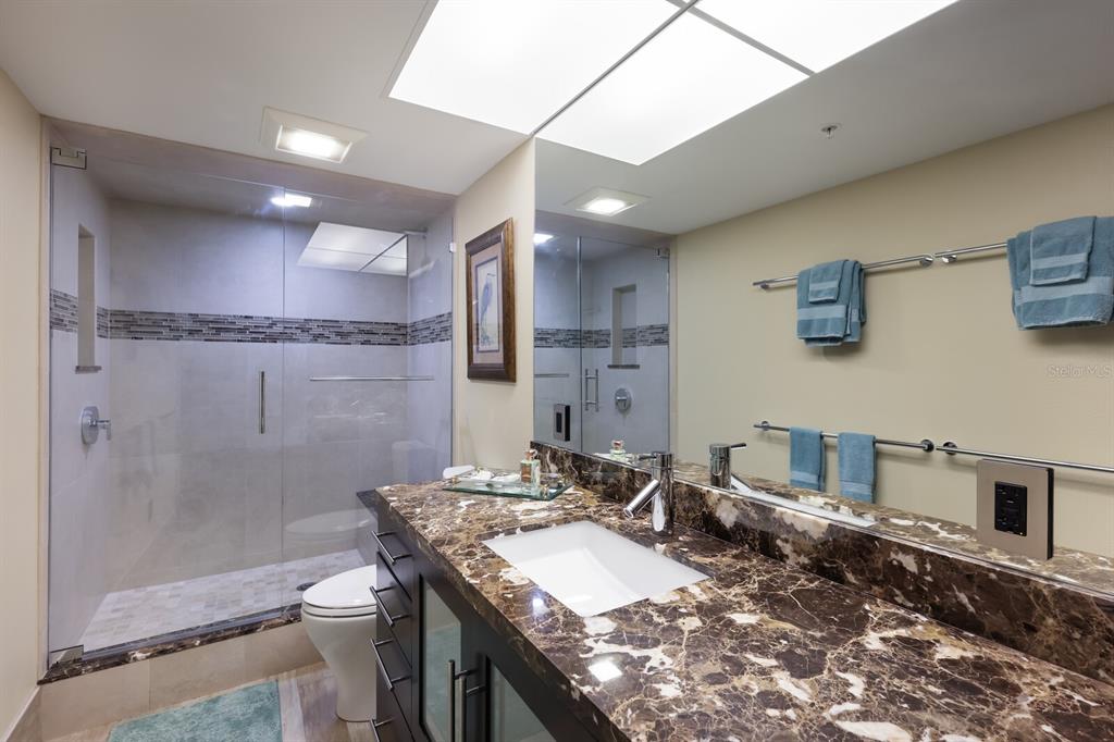 11000 Placida Road, Unit 2203 Placida, FL 33946 - Photo 27 of 64 a bathroom with a granite countertop sink a toilet a mirror and shower