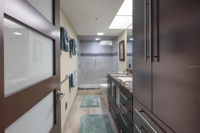 a bathroom with a sink a toilet a large mirror and shower