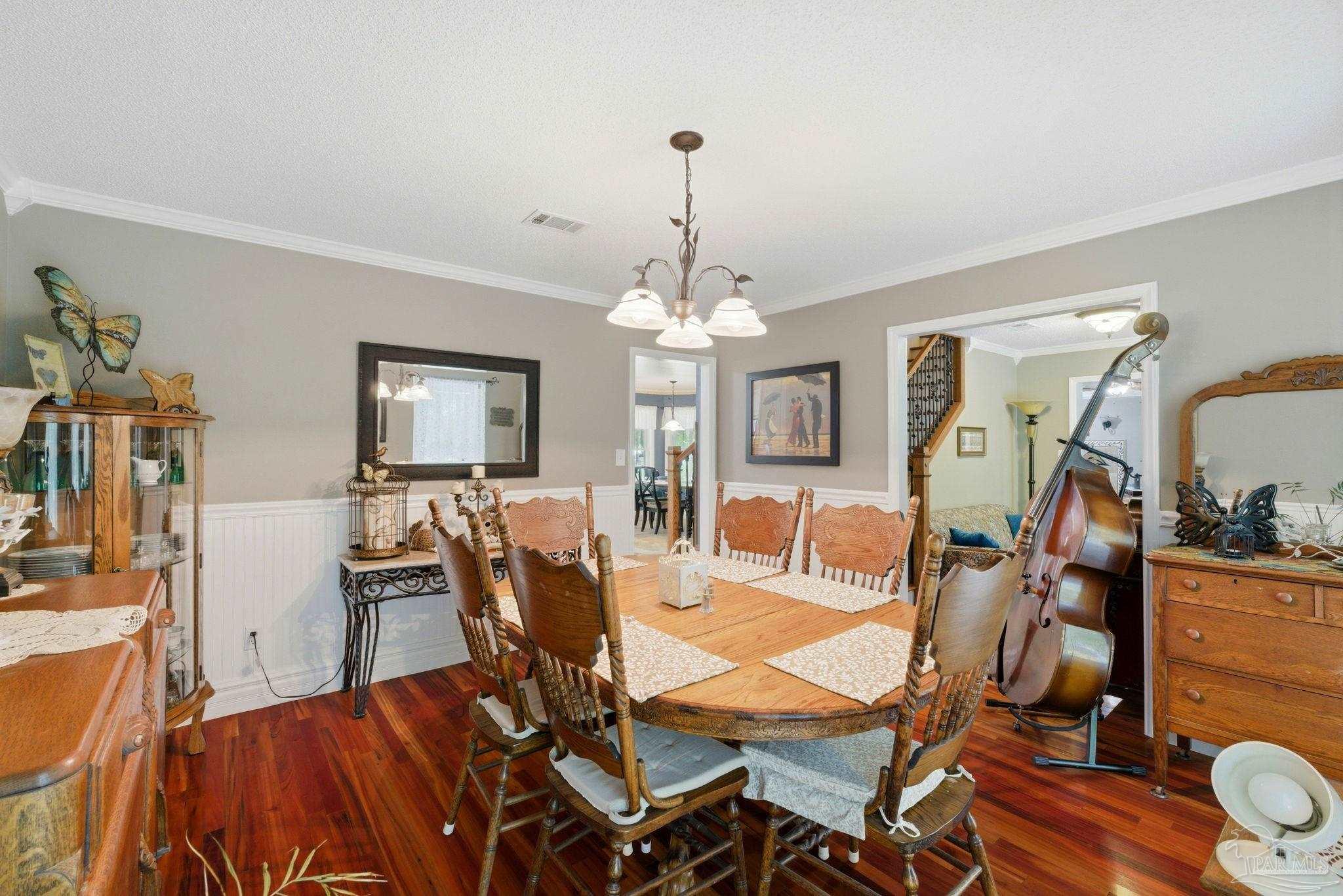 6930 Summit Way Milton, FL 32570 - Photo 14 of 71 a dining room with wooden floor a chandelier a wooden table and chairs