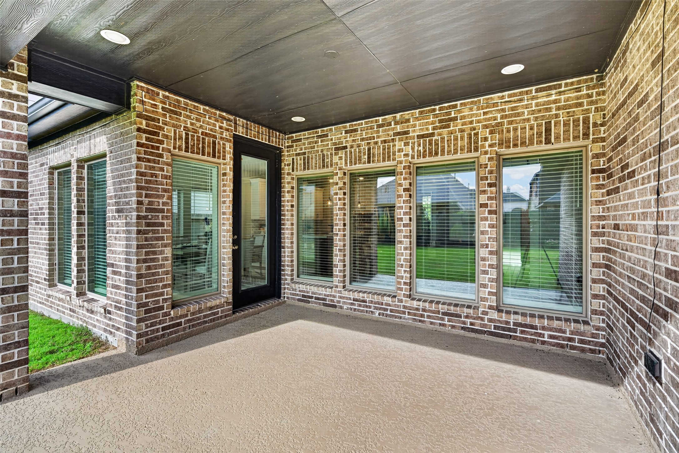 4207 Ana Ridge Lane Fulshear, TX 77441 - Photo 32 of 37 Spacious covered patio with stone accents and large glass doors, creating a seamless transition for indoor-outdoor family entertaining!