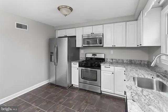 a kitchen with stainless steel appliances granite countertop a sink a stove a microwave and refrigerator