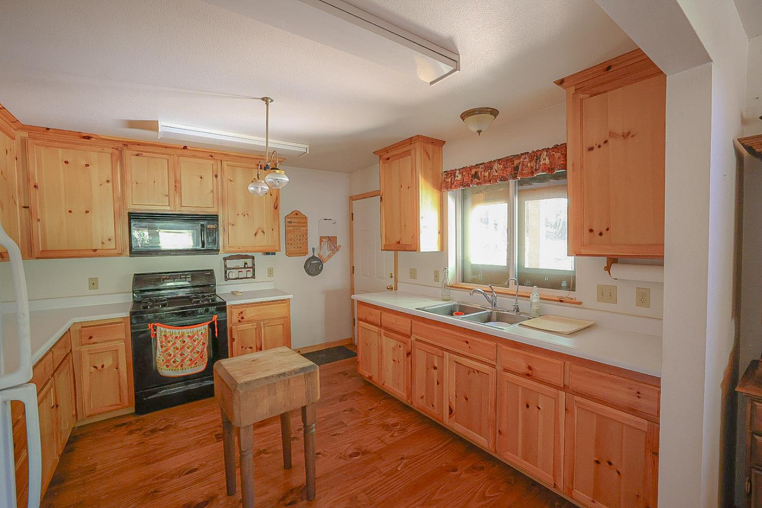 67922 Beasore Road Bass Lake, CA 93604 - Photo 12 of 39 a kitchen with stainless steel appliances granite countertop a stove top oven a sink dishwasher a dining table and chairs with wooden floor