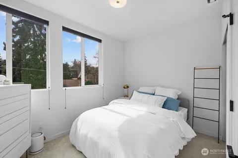 a large white bed in a bedroom next to a window