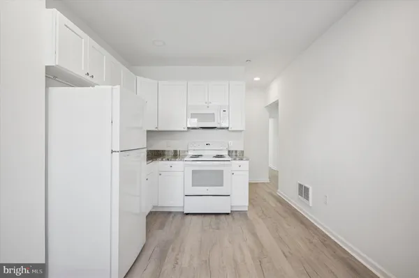 a kitchen with a white stove top oven and white kitchen