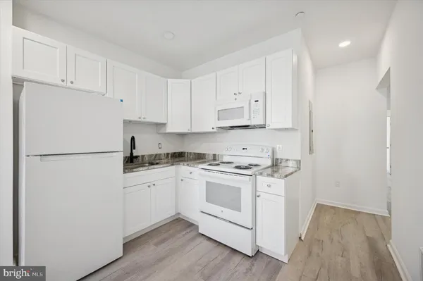 a kitchen with white cabinets and white appliances