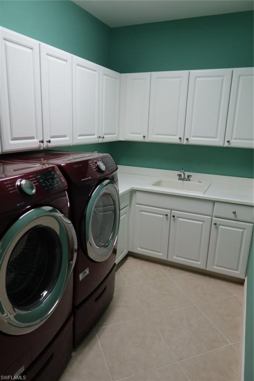 7168 Lemuria Circle, Unit 1701 Naples, FL 34109 - Photo 32 of 39 Dedicated laundry area featuring white shaker-style cabinetry, a built-in utility sink, light-toned countertop, and neutral-toned tile flooring
