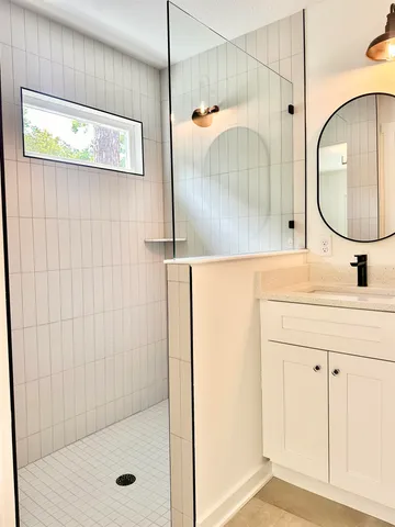 a bathroom with a sink a mirror a vanity and shower