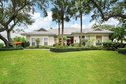 a front view of a house with a garden and trees