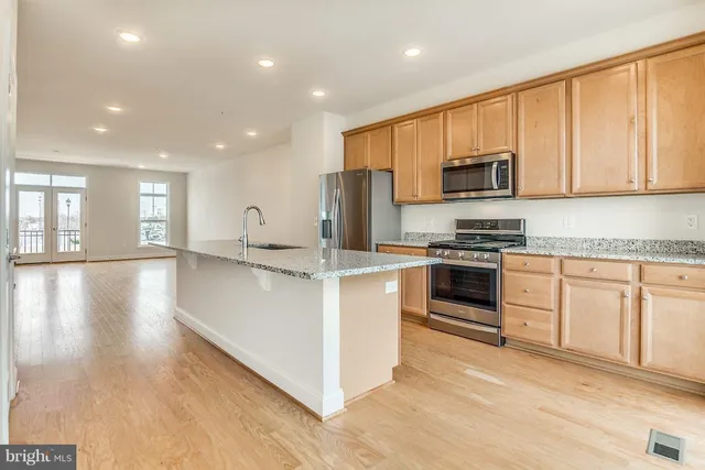 a large kitchen with stainless steel appliances granite countertop a stove a sink dishwasher and a microwave with wooden floor