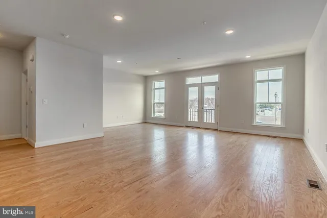 a view of an empty room with wooden floor and window