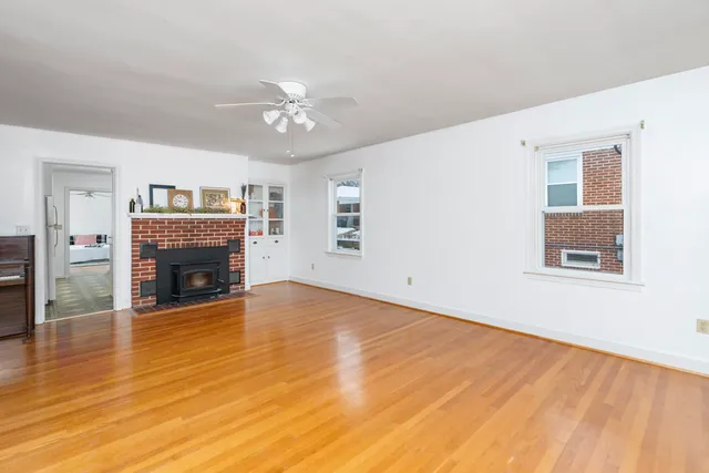 a view of a livingroom with a fireplace a chandelier and wooden floor