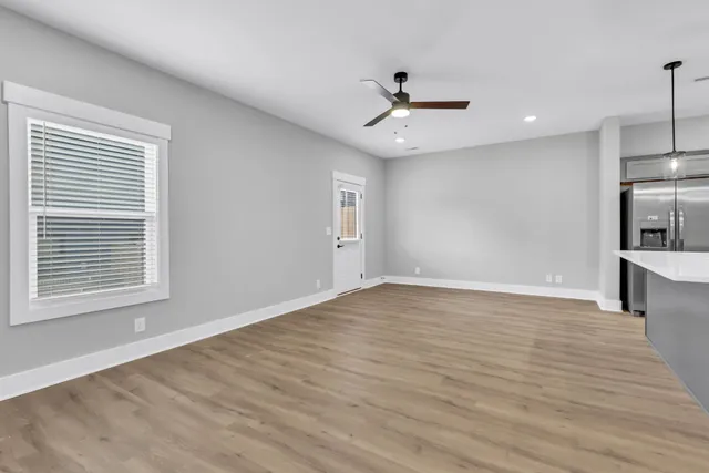 a view of an empty room with wooden floor and a window