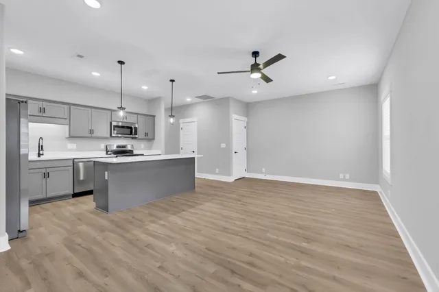 a large kitchen with stainless steel appliances kitchen island a sink dishwasher a refrigerator and a oven with white cabinets