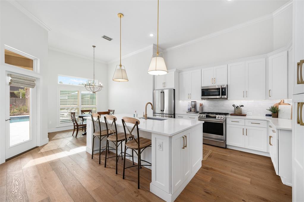 13549 Northwest 9 Road Newberry, FL 32669 - Photo 11 of 42 a kitchen with stainless steel appliances kitchen island granite countertop a stove a sink a center island a dining table and chairs
