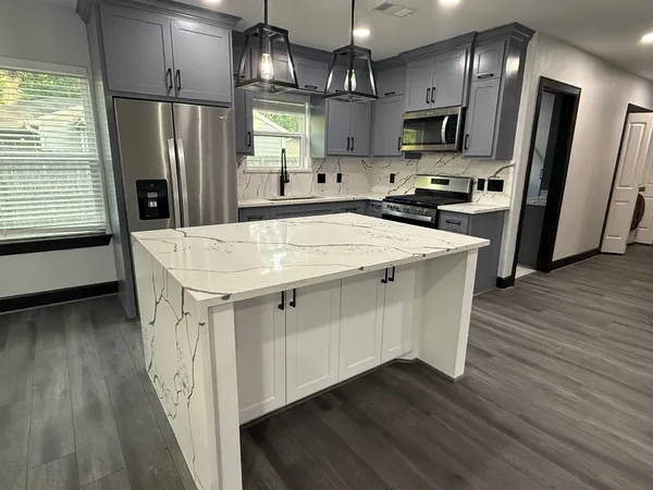 a kitchen with stainless steel appliances a refrigerator sink and wooden floor