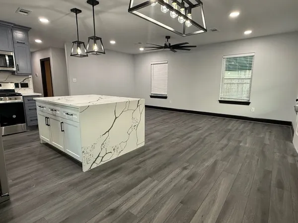 a kitchen with stainless steel appliances granite countertop a sink a stove and a wooden floors