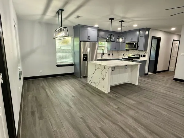 a large kitchen with cabinets wooden floor a window and stainless steel appliances