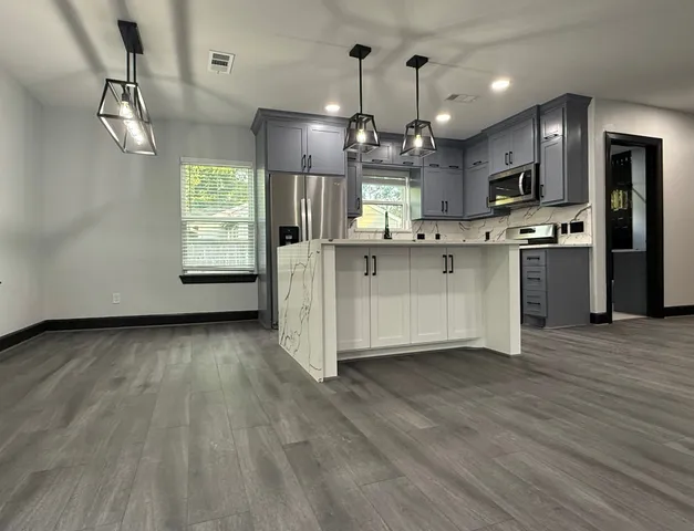 a kitchen with stainless steel appliances a refrigerator sink and wooden floor