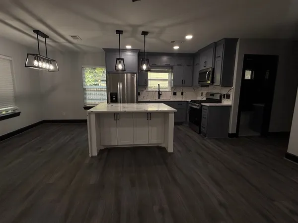 a large kitchen with a table chairs wooden floor and a ceiling fan