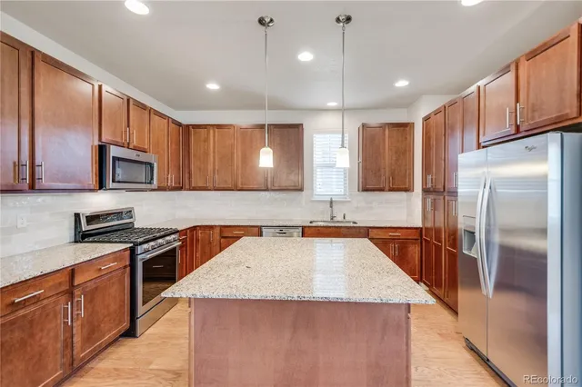 a kitchen with granite countertop stainless steel appliances cabinets a sink and a counter top space